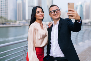 Business man and woman talking in urban city center working together taking selfie on the phone