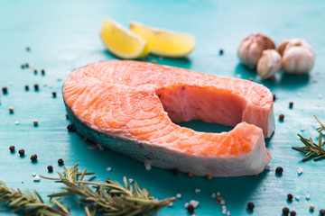 Raw salmon steak on wooden on blue background. Healthy food, diet and mediterranean cuisine concept