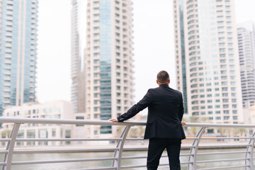 Rear view of young businessman standing against skyscrapers view.