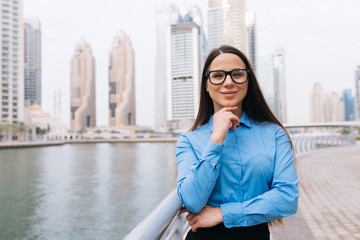 Portrait of a confident businesswoman with hands on chin on the skyscrapers background