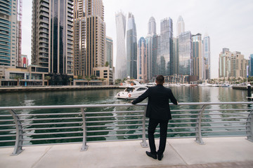 Fototapeta premium Rear view of ambitious entrepreneur looking at modern skyscrapers and enjoying city view