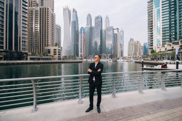 Successful young businessman wearing suit and sunglasses walking on street in business district