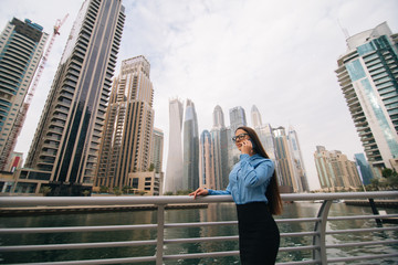 Portrait of a young attractive woman talk by mobile phone big city skyscrapers on background