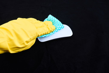 Photo of hand wearing yellow gloves disinfecting a digital mouse