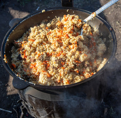 Pilaf with rice is cooked on a cast-iron cauldron.