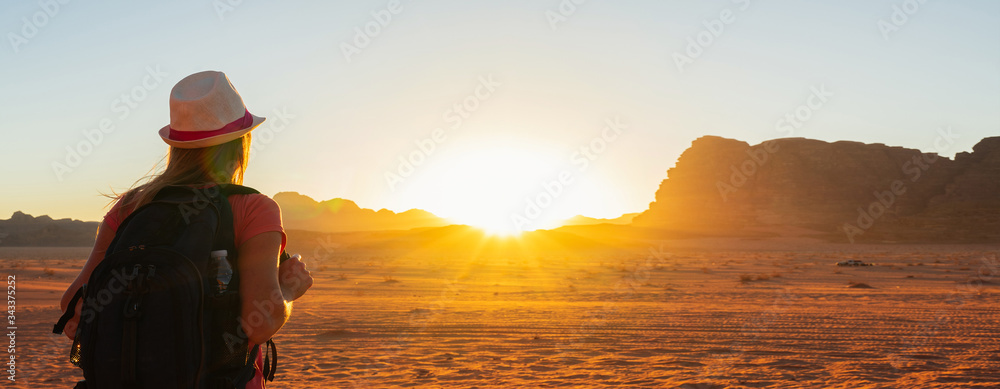 Wall mural Woman enjoying the beautiful sunset in the Wadi Rum desert in Jordan. Banner.