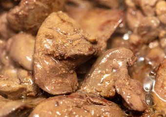 Chicken liver is fried in a pan.