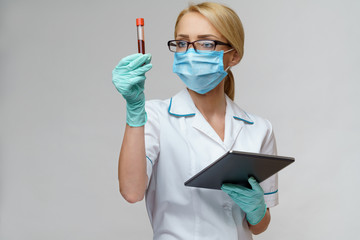 medical doctor nurse woman wearing protective mask and gloves - holding virus blood test and tablet pc