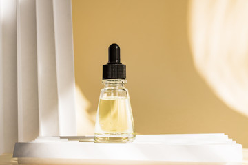 Dropper glass bottle with pipette. Mock up Essential liquid . On a beige pastel paper background.