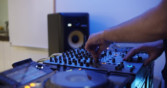 Dj playing music at home lit by a blue light