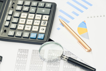 Business financial documents, office calculator and pen on the table. Numbers and graphs