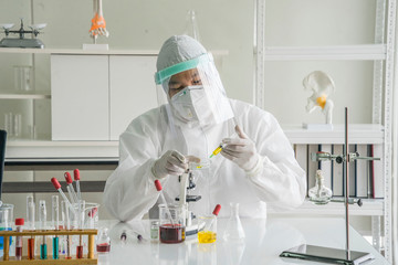 The doctor wore germicidal clothing PPE, wear a face mask, and and face shield  put a test tube on...