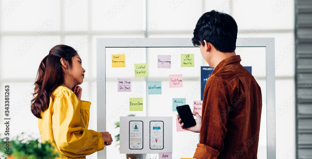 Aufkleber ux developer and ui designer presenting  and testing mobile app interface design on whiteboard in meeting at modern office.Creative digital development mobile app agency