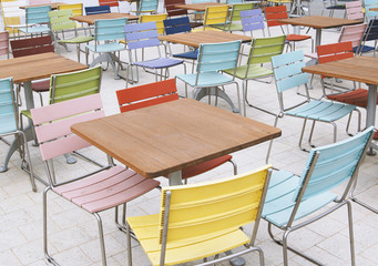 empty deserted street cafe or outdoor restaurant tables with multicolored chairs - off season or economy crisis concept