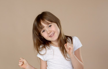 Cute little girl in white tshirt dancing, smiling and having fun in studio session