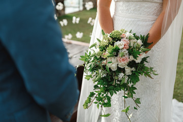 Crop man in elegant suit and green boutonniere and woman in beautiful peach color dress with big...