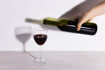 Pouring red wine into the glass against wooden background