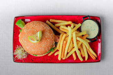 Burger with salmon and fries with sauce