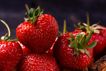 in the foreground, on a dark background, some delicious red strawberries in the shape of a heart
