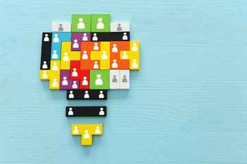 image of tangram puzzle blocks with people icons over wooden table ,human resources and management...