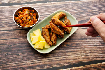 Fried chicken wings with Korean pickle kimchi on a wooden table