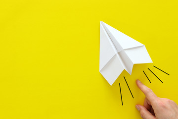 concept image of person hand directing paper plane over yellow background