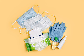 White medical masks and gloves with antibacterial wet wipes  and hand sanitizer on yellow background. Personal hygiene product for protection virus, flu, coronavirus, COVID-19