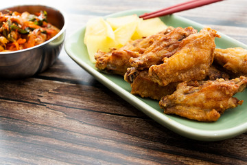 Fried chicken wings with Korean pickle kimchi on a wooden table
