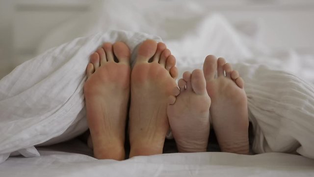 Couple loving in bed. Only feet in a frame. Love, sex concept.