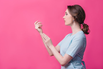 Beautiful girl gently touches her hands on a pink background in the studio. The concept of beauty, care, cosmetology and massage