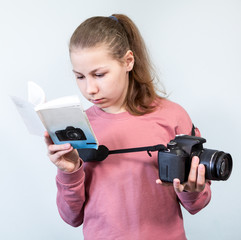 Preteen girl reading service manual book for her dlsr camera, beginner is learning photography,...