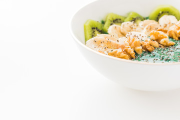 spirulina smoothie bowl with banana, walnuts, kiwi and chia seeds on white background