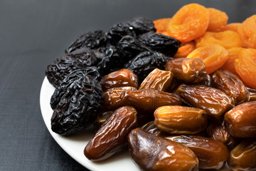 Dried fruits on a plate a on a black background