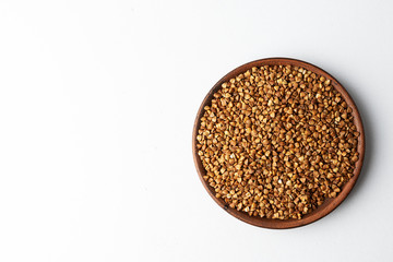 Buckwheat in a clay plate on a white background