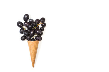 Uvas negras con un cono de oblea sobre fondo blanco aislado. Vista superior. Copy space
