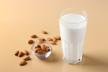 Glass with fresh almond milk and almonds on beige background, Healthy vegan milk replacer, Horizontal format, Space for text, Closeup