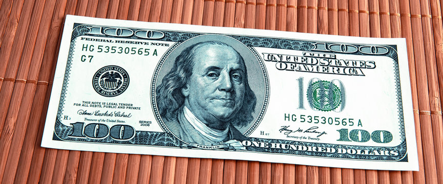 A hundred dollars bill in close-up on a bambuk mat