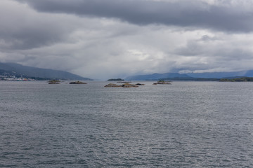A mystical fjord in Norway with mountains and fog hanging over the water in a beautiful monochrome blue color.