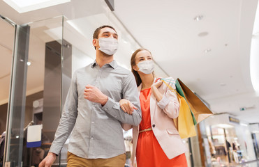 sale, consumerism and pandemic concept - happy young couple wearing face protective medical mask...