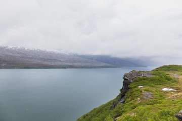 Fototapeta premium Beautiful view of the Norwegian fjords with turquoise water surrounded by cloudy sky, selective focus