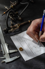 A male hand draws a drawing on a table in a car workshop.