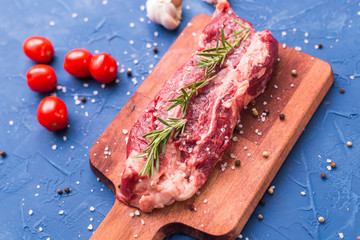 Raw beef fillet steaks with herbs and spices on wooden background