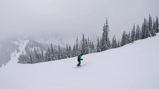 Man Splitboarding Up Steep Slope Exploring Mountains in Winter Season