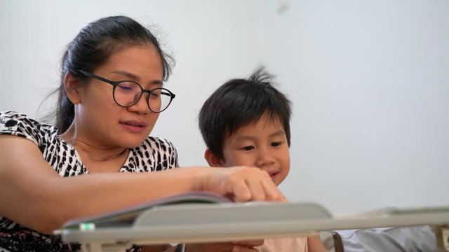 Asian boy about 4 years old reading book and study at home with his mother