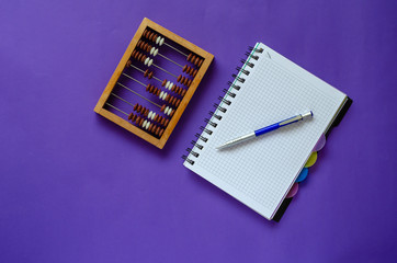 Wooden abacus, notebook and pen on the table