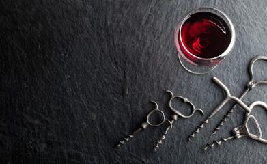 .Glass of red wine and corkscrews on a dark background..Glass of red wine and corkscrews on a dark background.