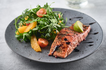 Hot smoked salmon with arugula salad, cherry tomato and orange. Healthy eating.