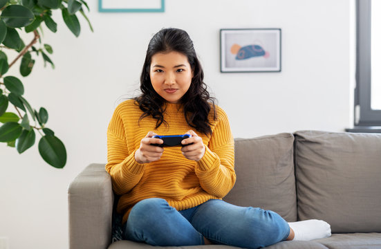 People And Leisure Concept - Asian Young Woman With Gamepad Playing Video Game At Home