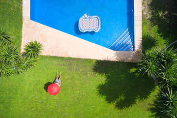 plano  cenital de piscina, colchoneta y hombre tomando el sol en el jardín. fotografía con drone.