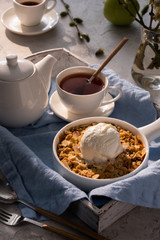 Apple crumble with a scoop of vanilla ice cream and tea on a wooden tray. Breakfast concept